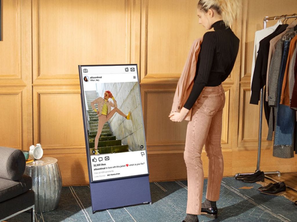 TV displaying an Instagram page and a woman standing next to it