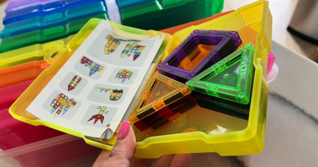 Frau zeigt einen gelben Behälter aus einem Simply Tidy Rainbow Photo and Craft Keeper voller Spielzeugteile