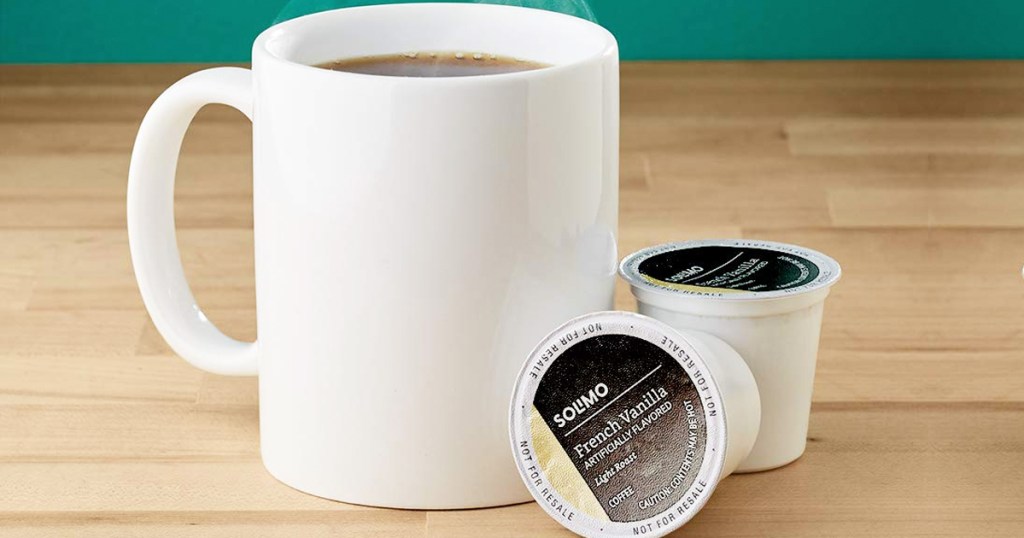 two k-cup pods on table next to mug of coffee