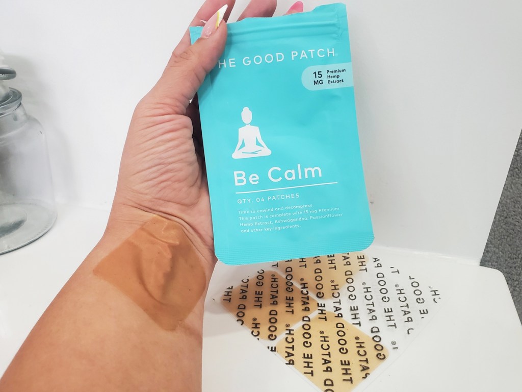 hand holding pack of The Good Patch Be Calm patches with patch on wrist