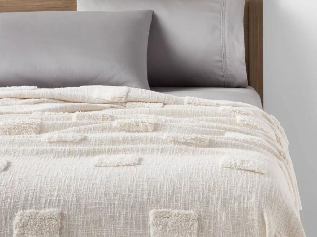 White blanket with tufted areas on a bed