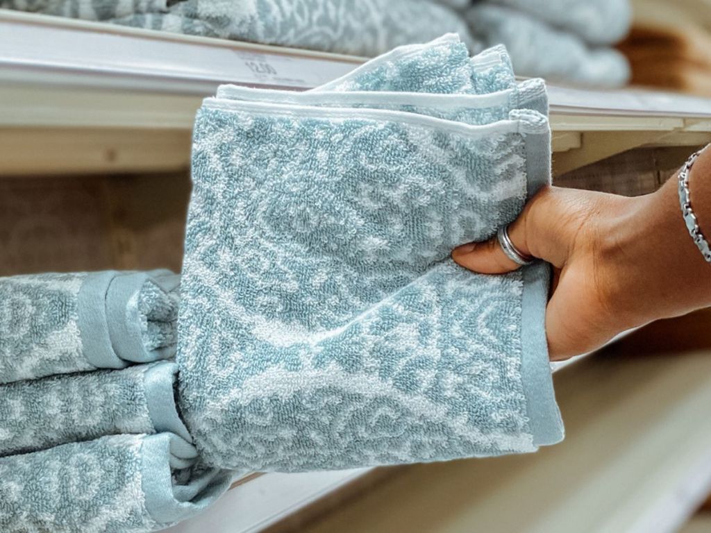 hand holding a folded Threshold Hand Towel in a light blue and white print