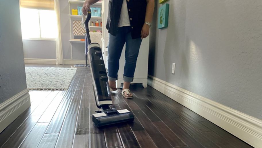 Woman using a vacuum on hardwood flooring