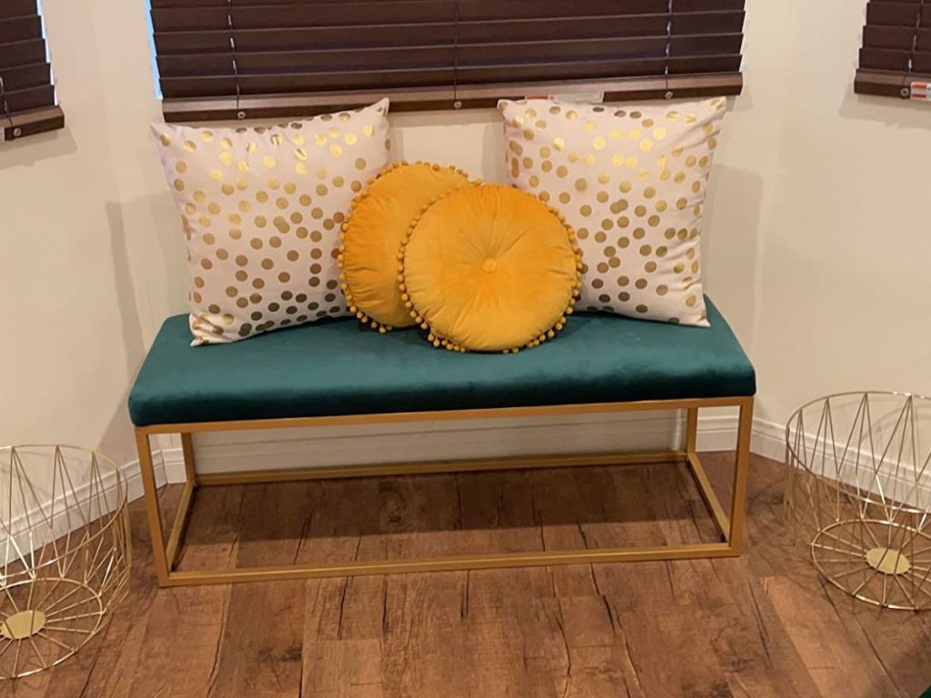 Upholstered Bench with pillows on it by a window