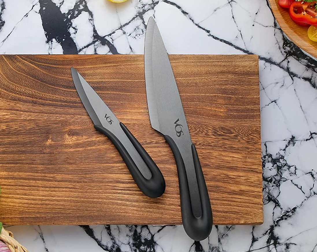 Two knives with black handles sitting on a cutting board