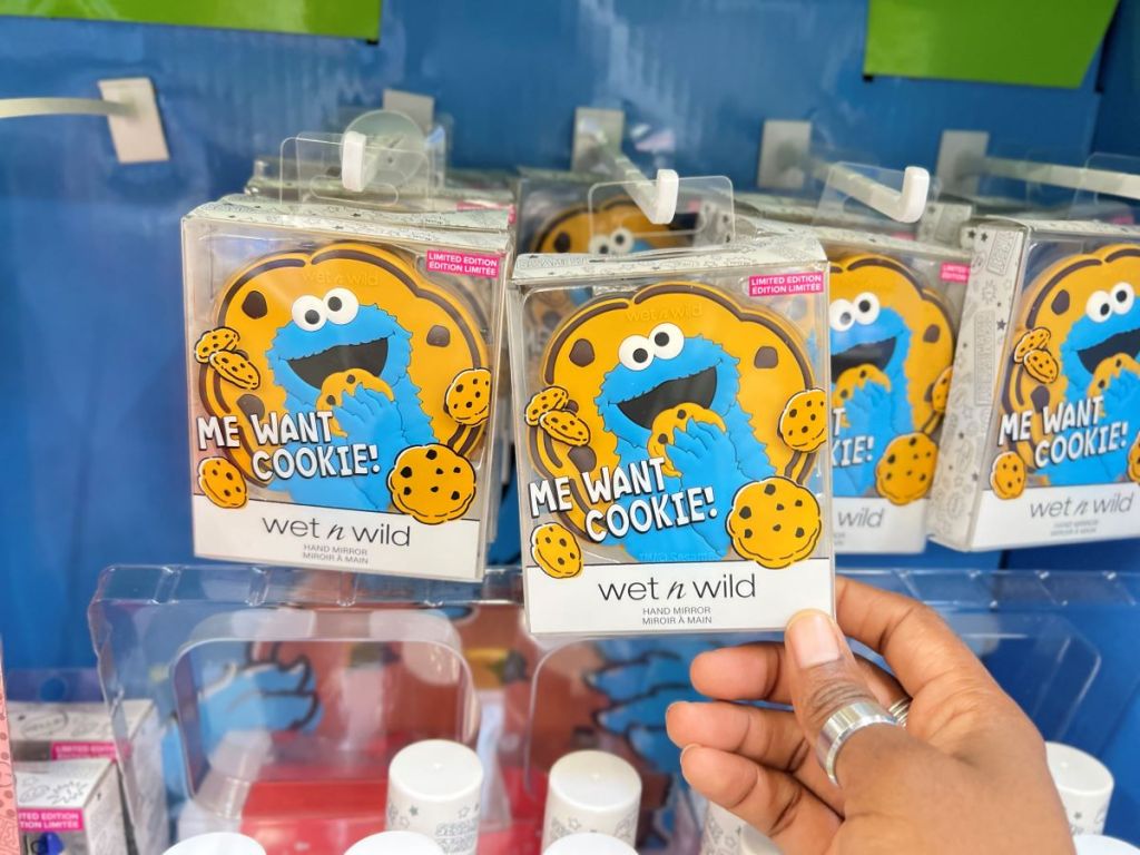 Hand holding a hand mirror that has Cookie Monster on it