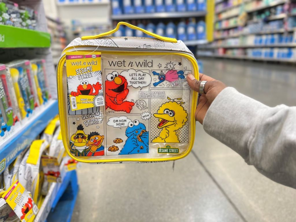 Hand holding a clear makeup bag with Sesame Street characters printed on it