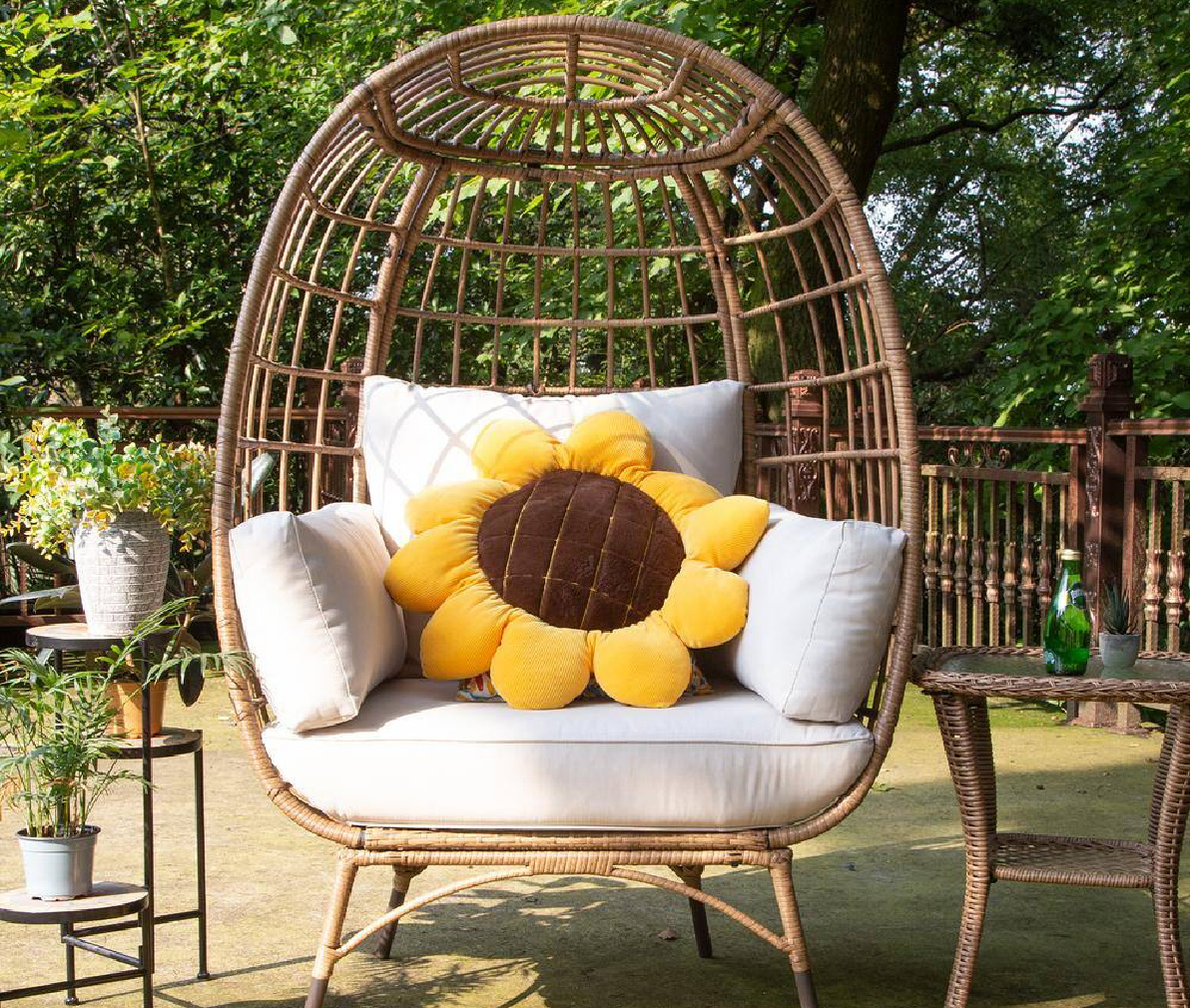  Wicker Indoor Outdoor Egg Lounge Chair with Beige Cushions and sunflower cushion sitting outside