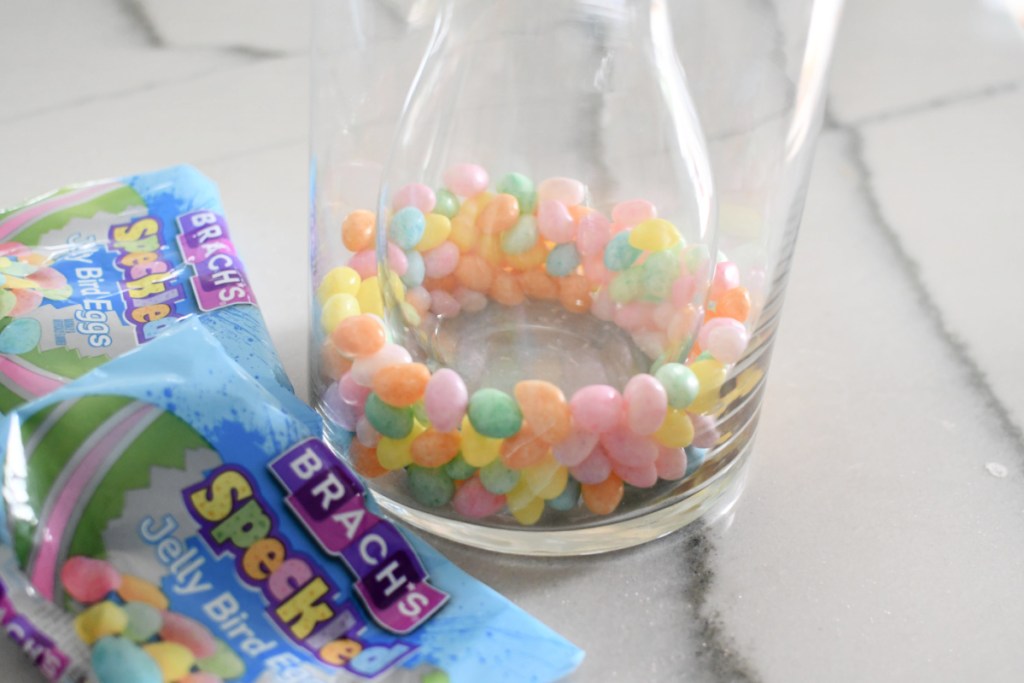 adding jelly beans to glass vase