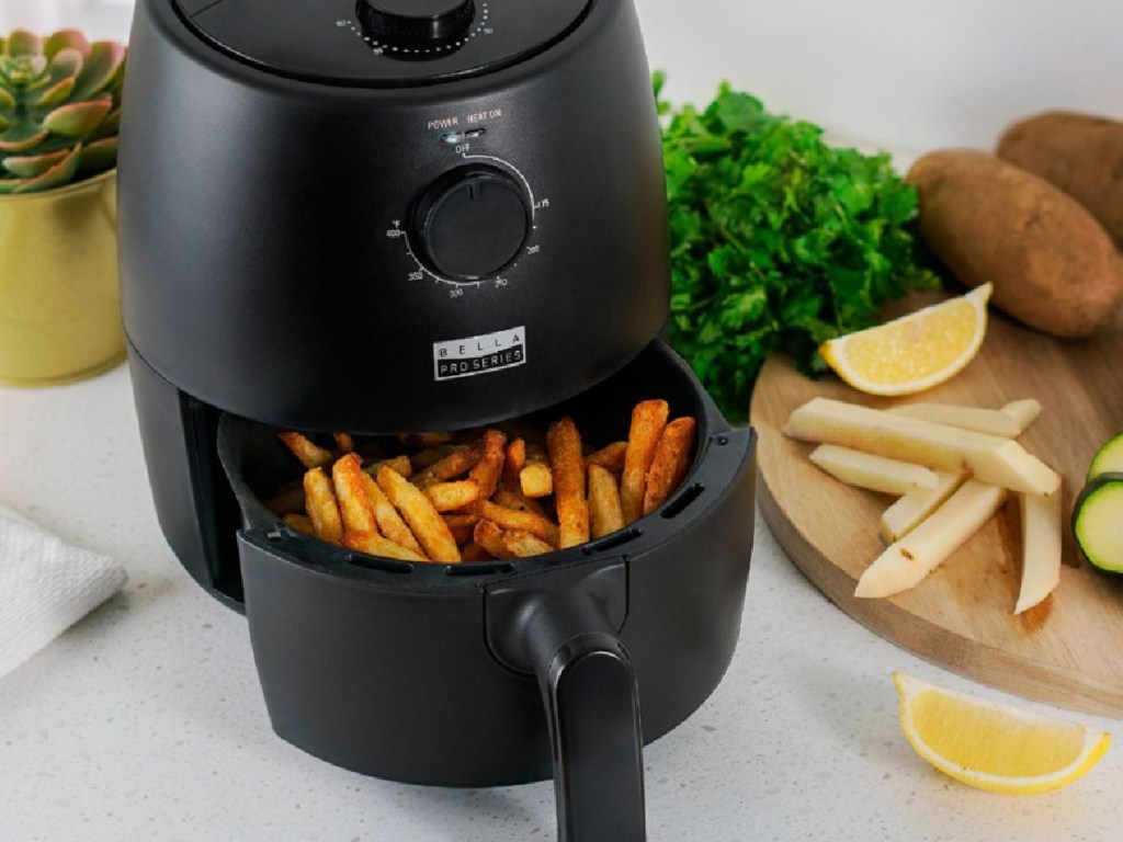 air fryer with French fries in it and food surrounding it