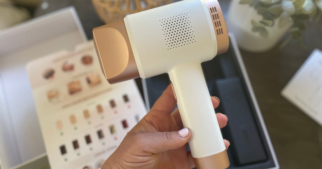 hand holding white and rose gold laser hand removal tool
