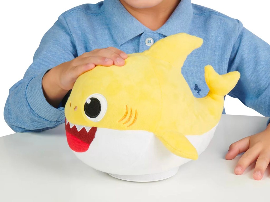 boy playing with yellow baby shark plush