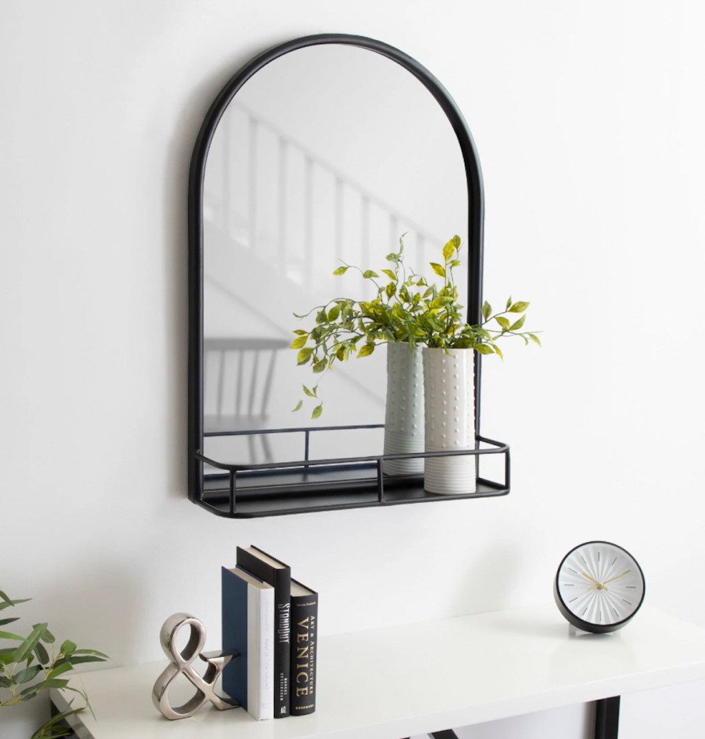 black arch mirror with shelf and plant
