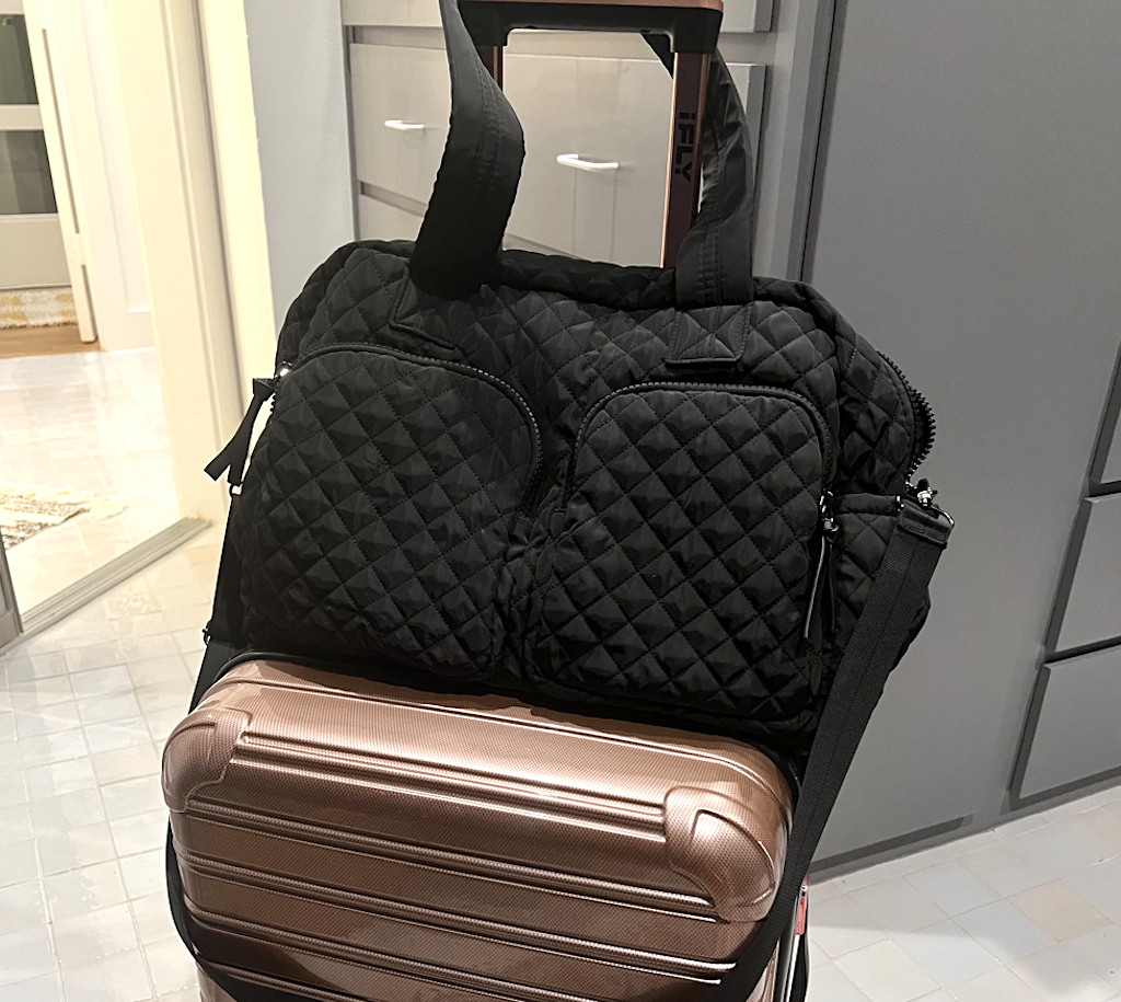 putting a black weekender bag on luggage 