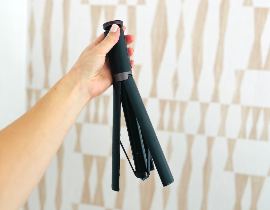hand holding a black collapsible tripod