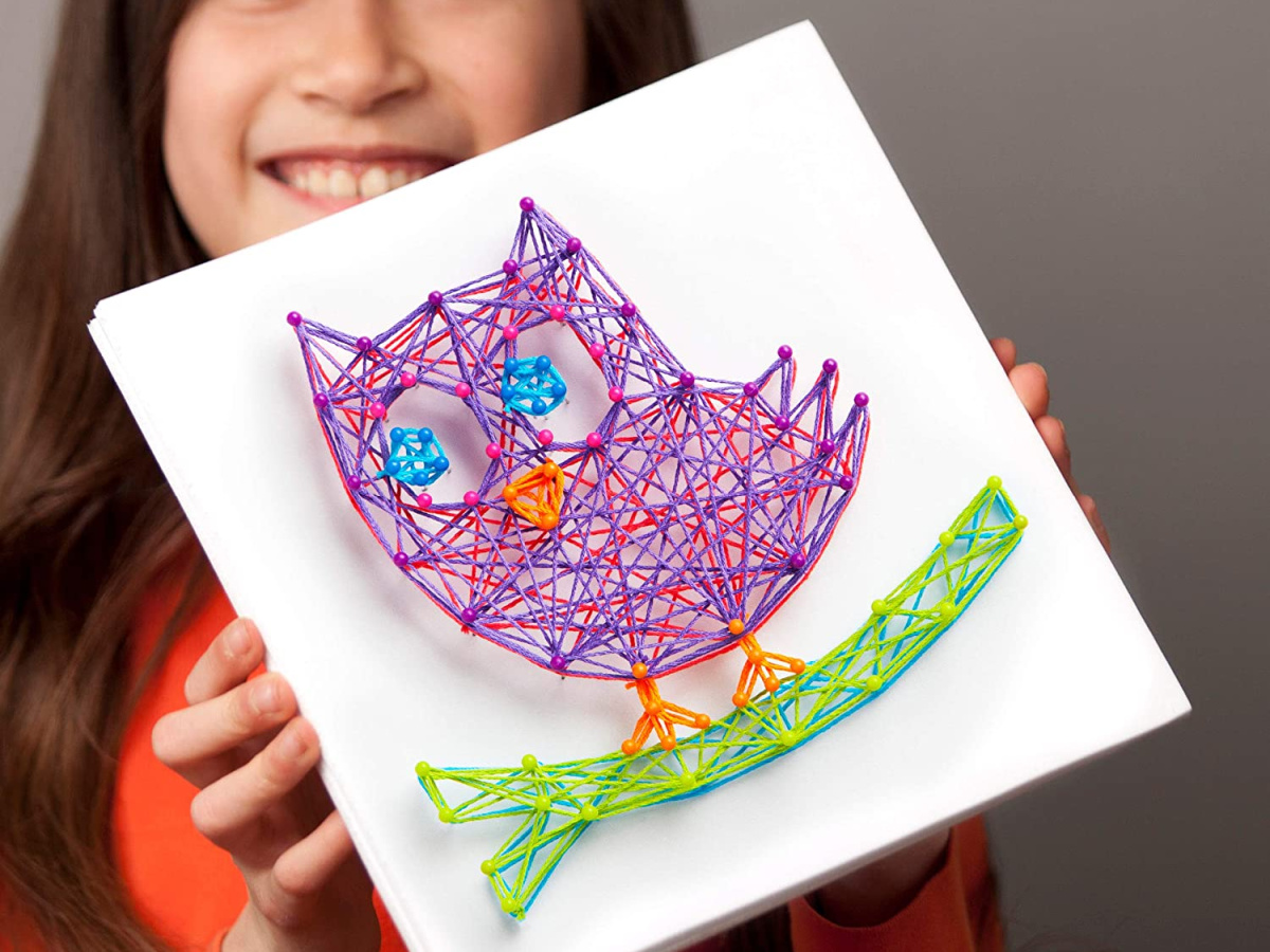 girl holding up a craft-tastic string art owl