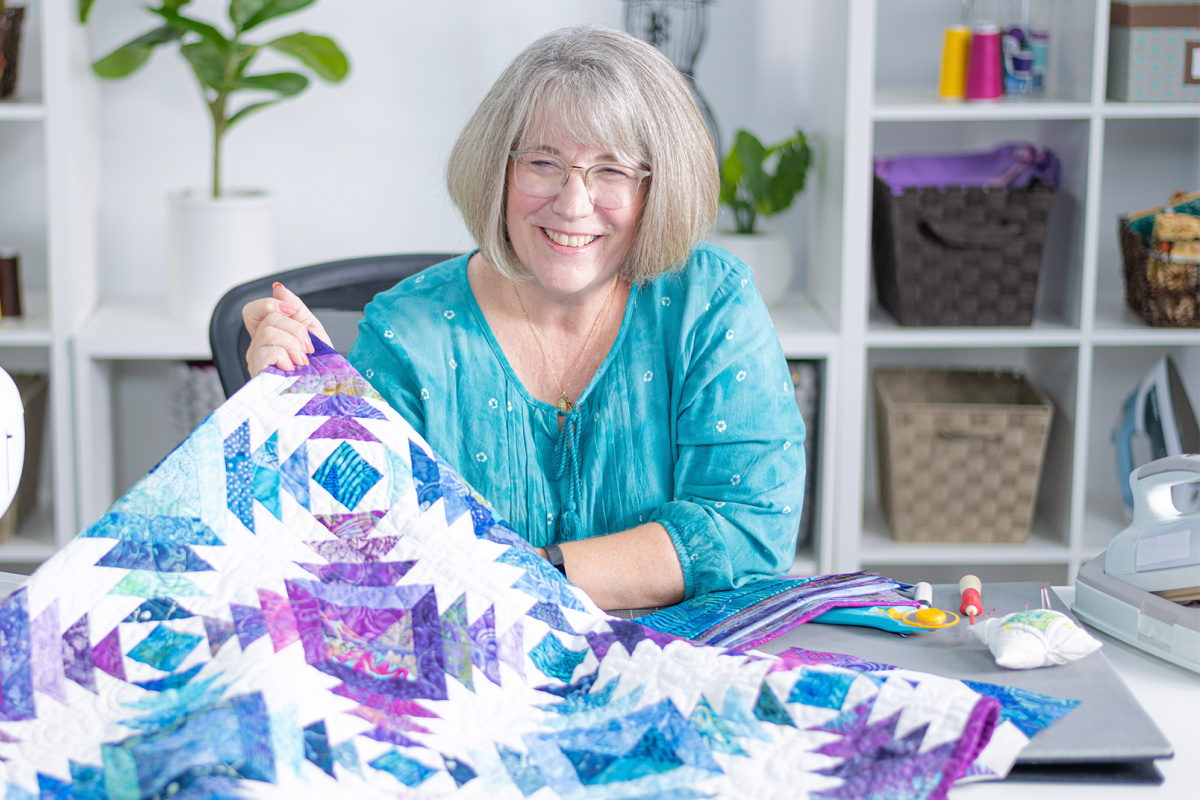 woman showing off a colorful quilt