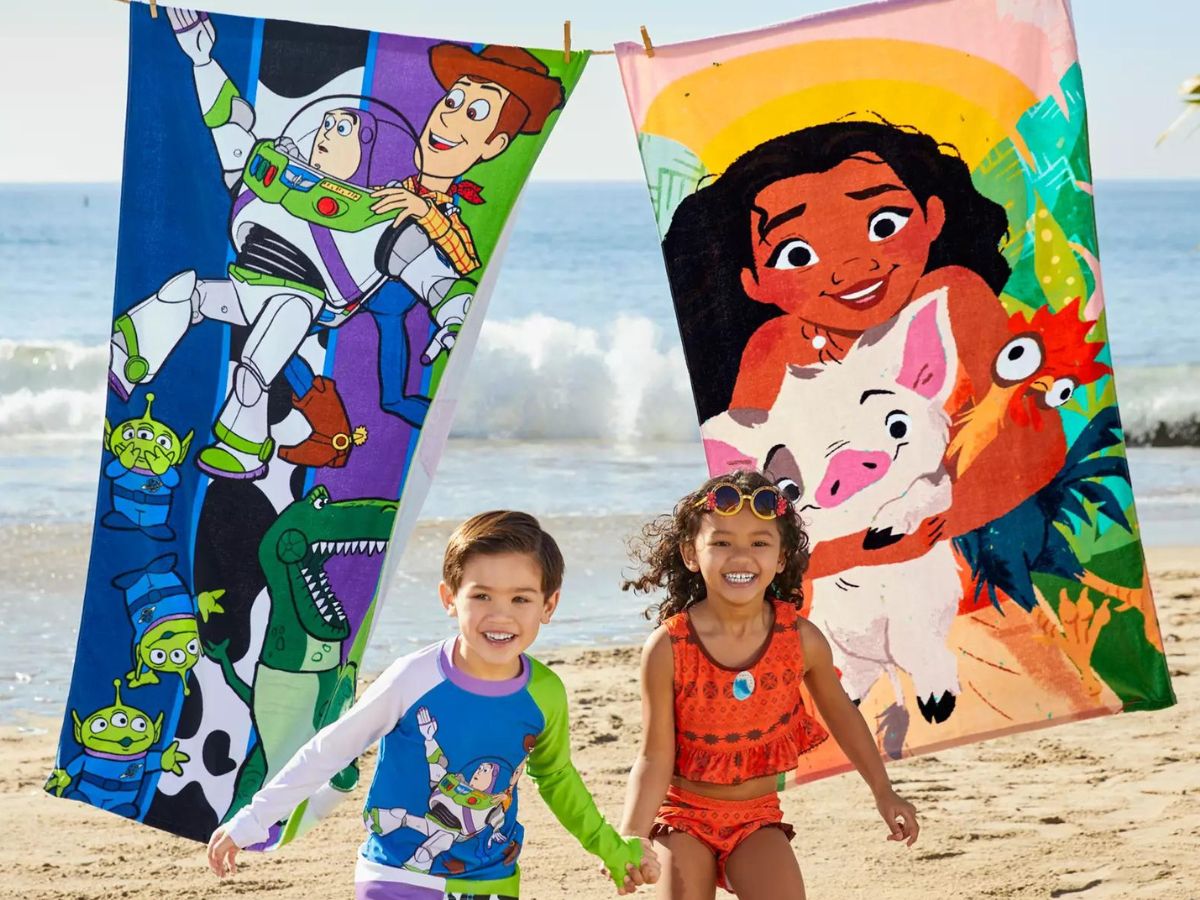 toy story and moana beach towels hanging on clothes line with kids running under them