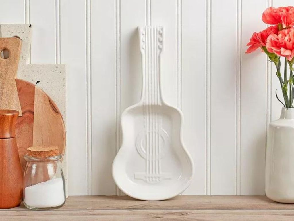 white ceramic guitar spood holder placed on wood table leaning on white wall