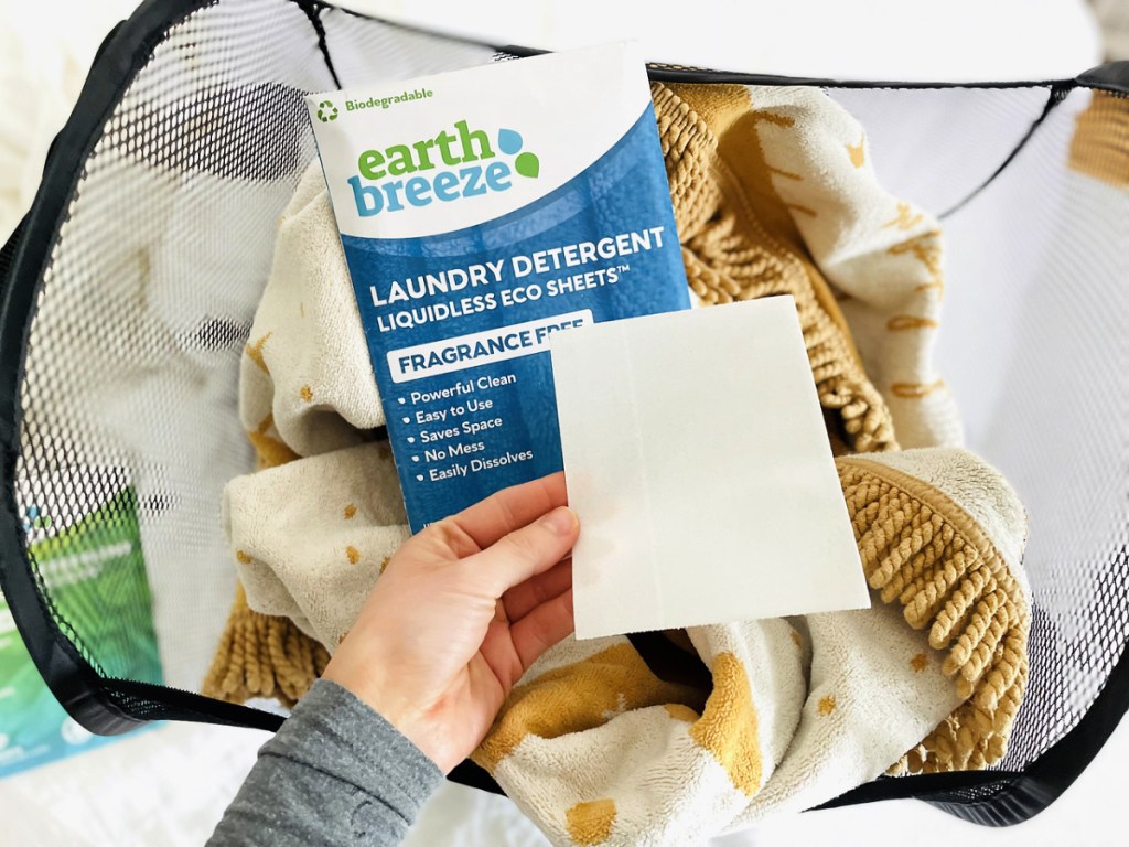 womena holding earth breeze laundry sheets over a hamper