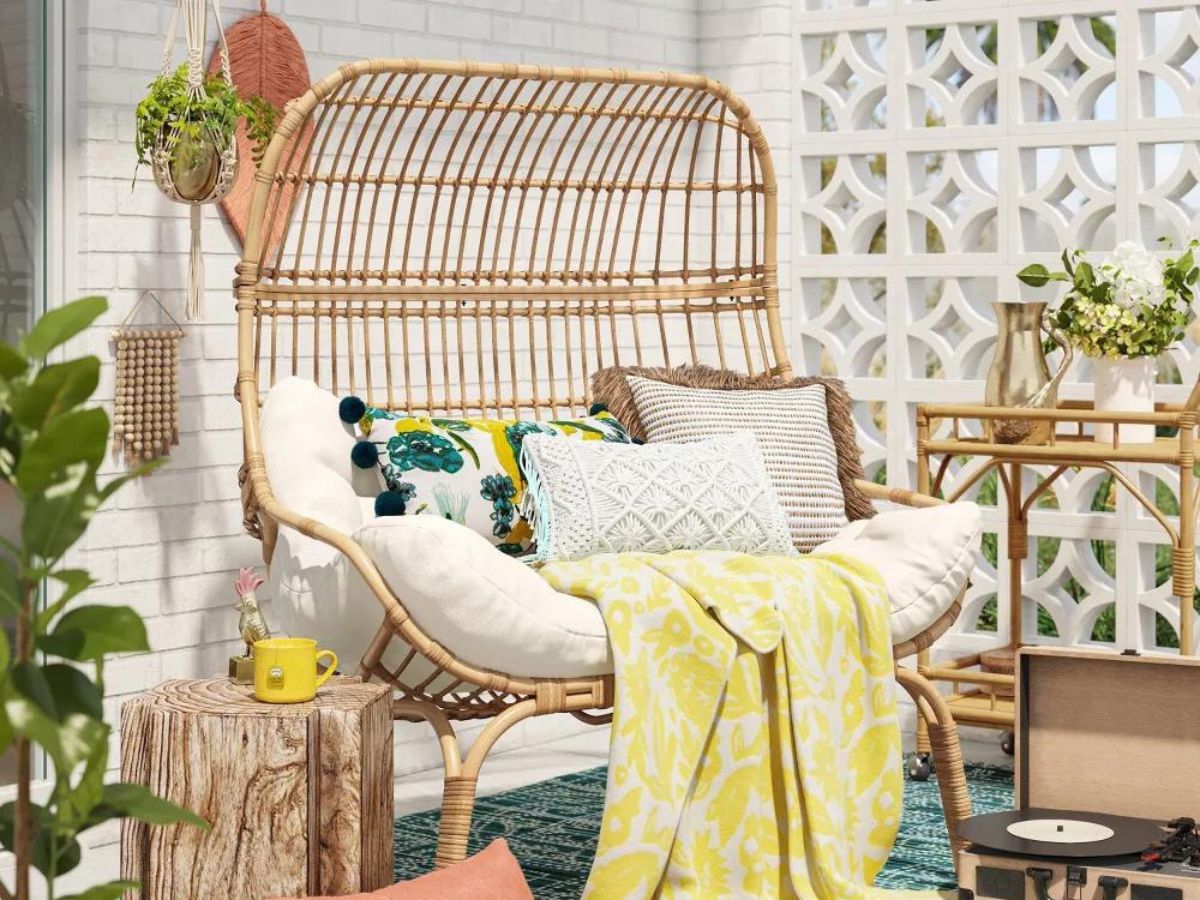 wicker egg chair with white cushion and throw pillows with yellow blanket 