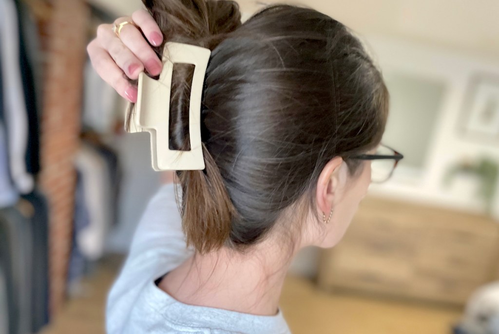woman holding white claw clip from hair