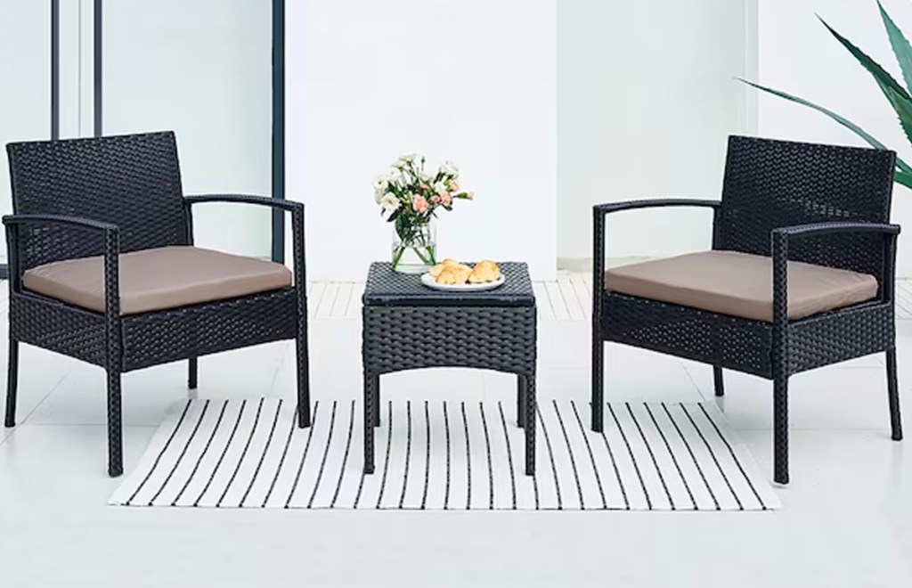 two black patio chairs with table on porch with striped rug 