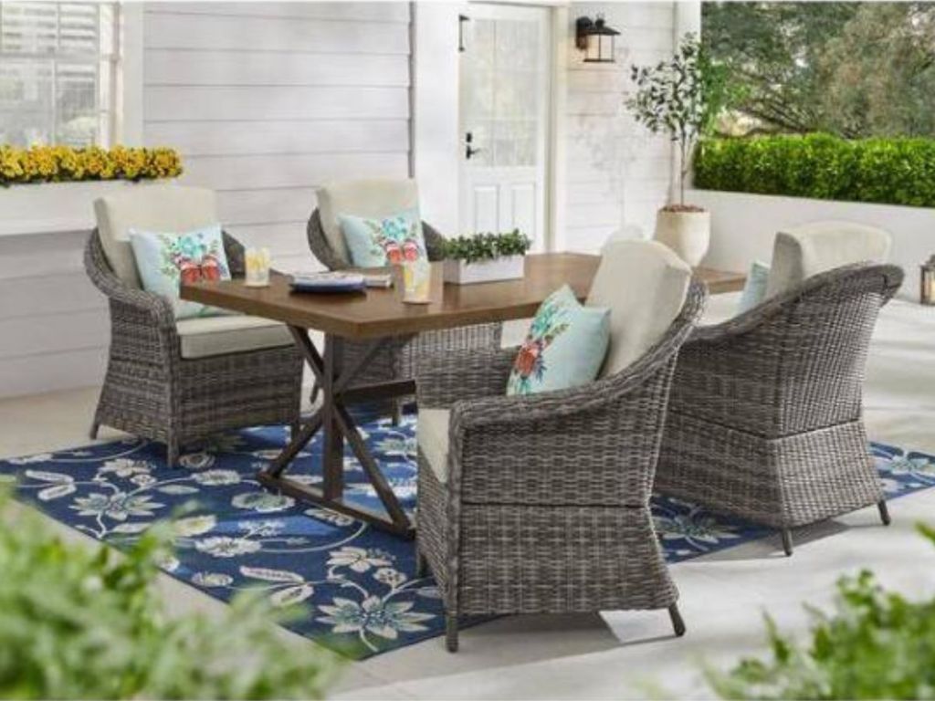wood table with four wicker chairs with gray cushions dining set on patio