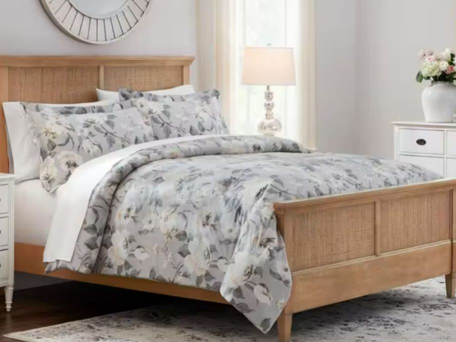 grey floral bedding set on a bed with a natural wood frame and headboard