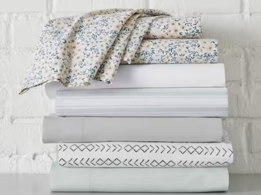 sets of cotton bed sheets in different colors and patterns stacked