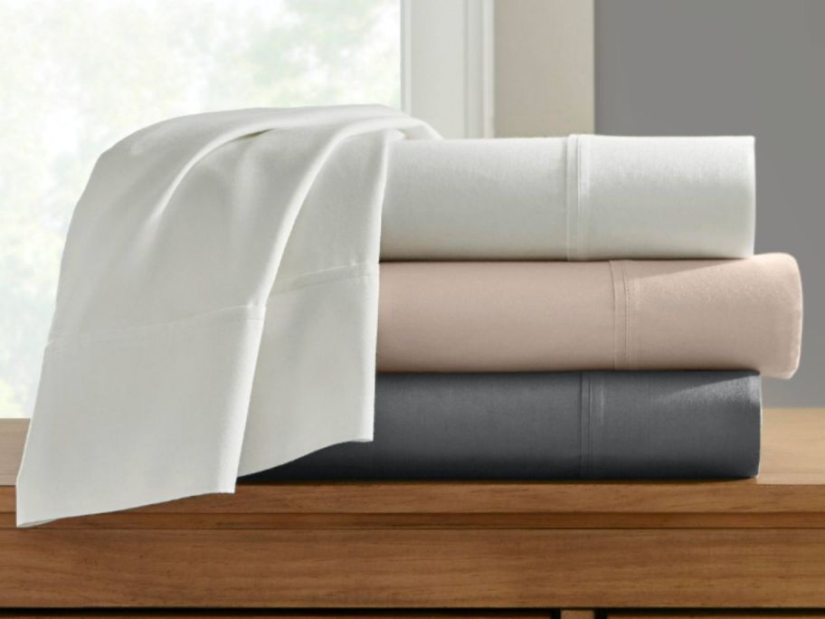 white, pink and grey sheet sets stacked on top of each other