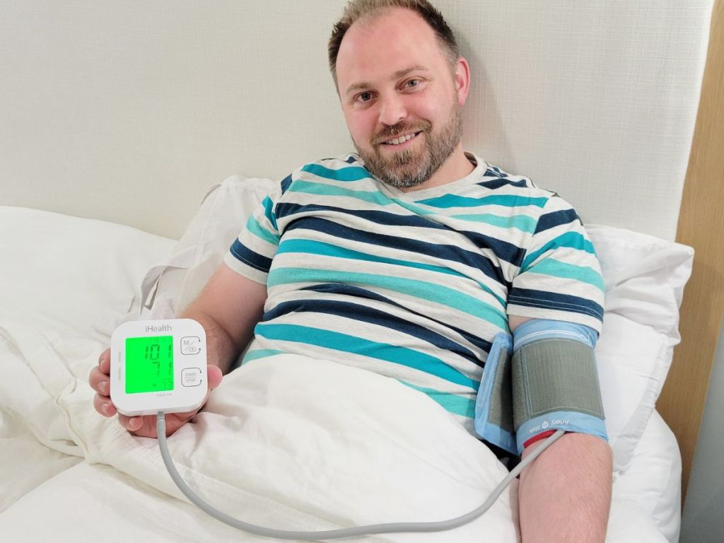 man sitting in bed using the iHealth Track Blood Pressure Monitor 