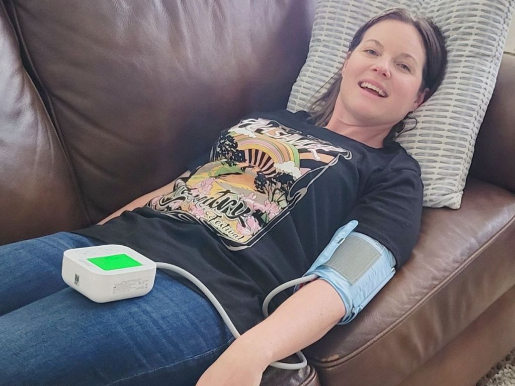 woman laying down taking her blood pressure with the iHealth Track Blood Pressure Monitor 