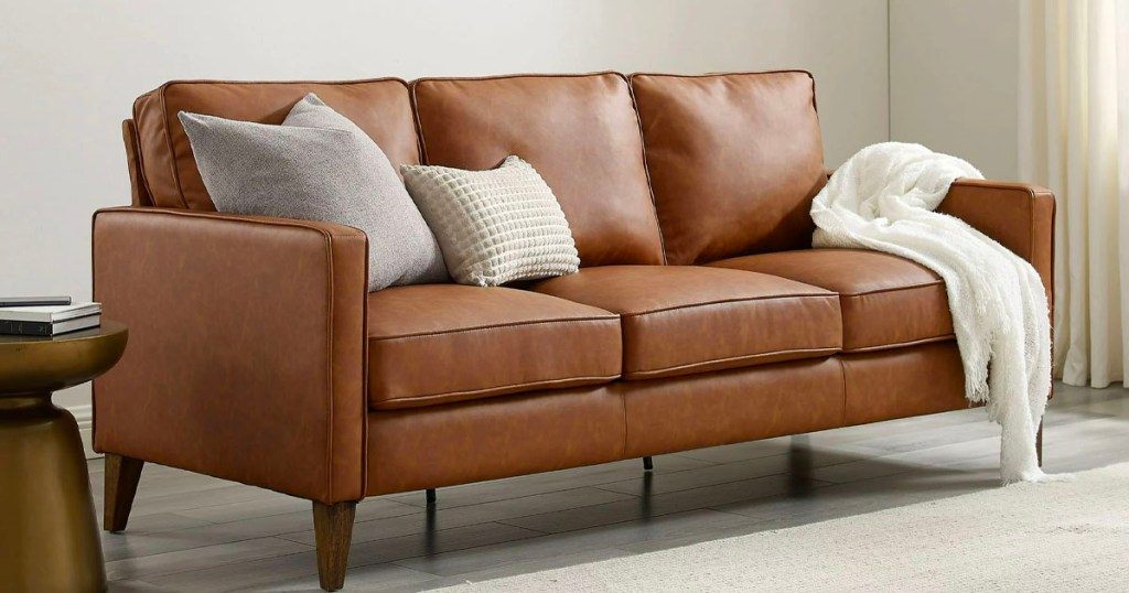 brown leather sofa with white pillows and blanket