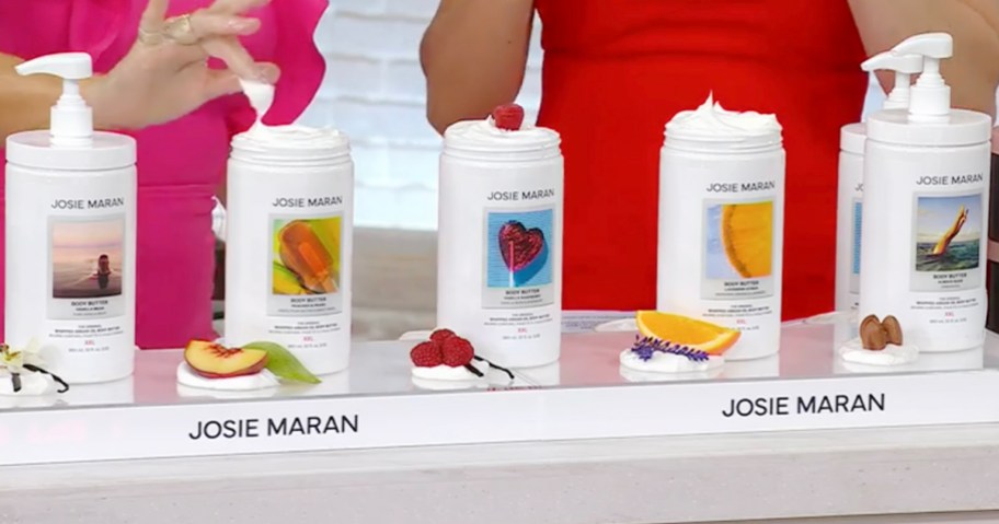 5 josie maran body butters sitting on countertop with two women in the background