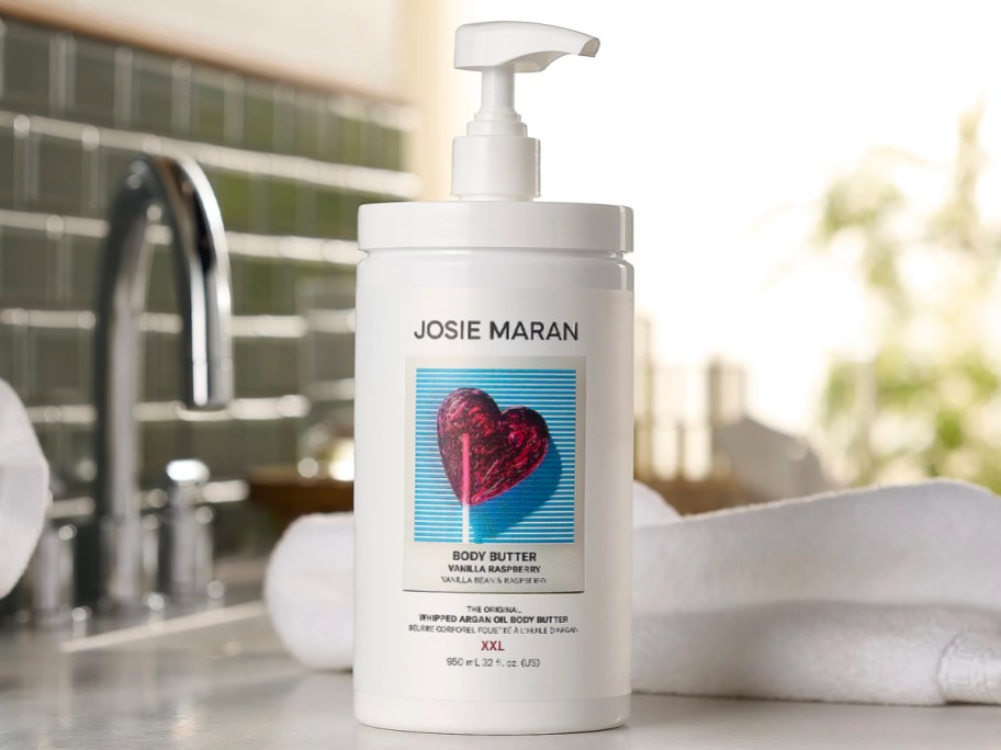 vanilla raspberry josie maran body butter with pump sitting on bathroom counter with washcloth in background