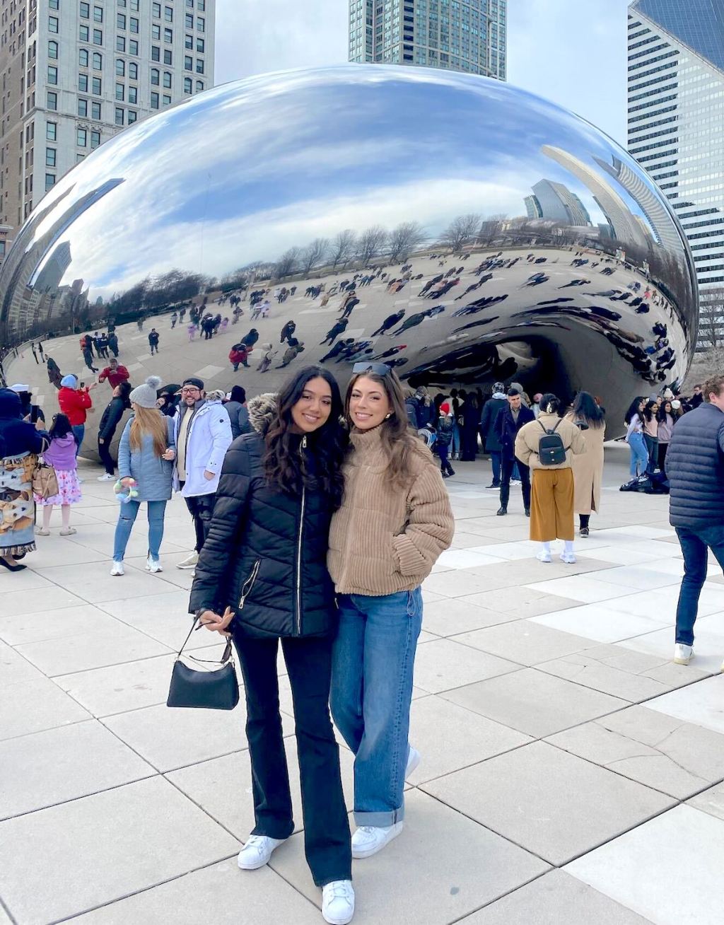 two women standing in front of silver bean cloud gate sculpture in chicago