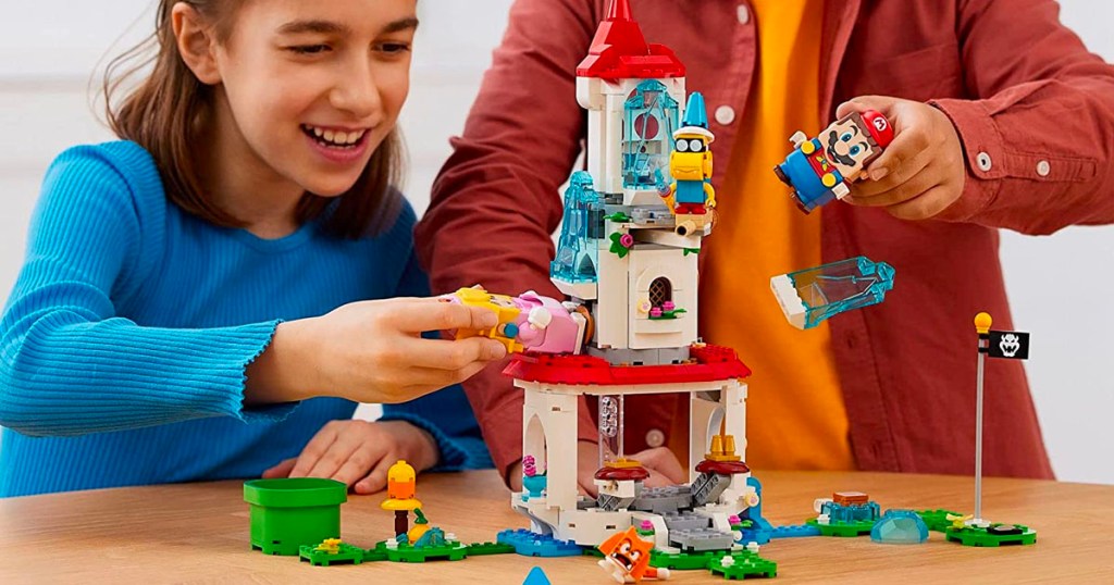 two kids building and playing with super mario lego set