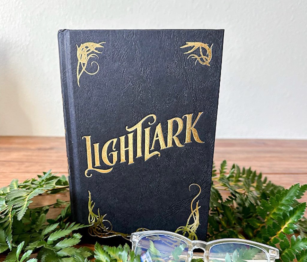 lightlark book on wood table with greenery