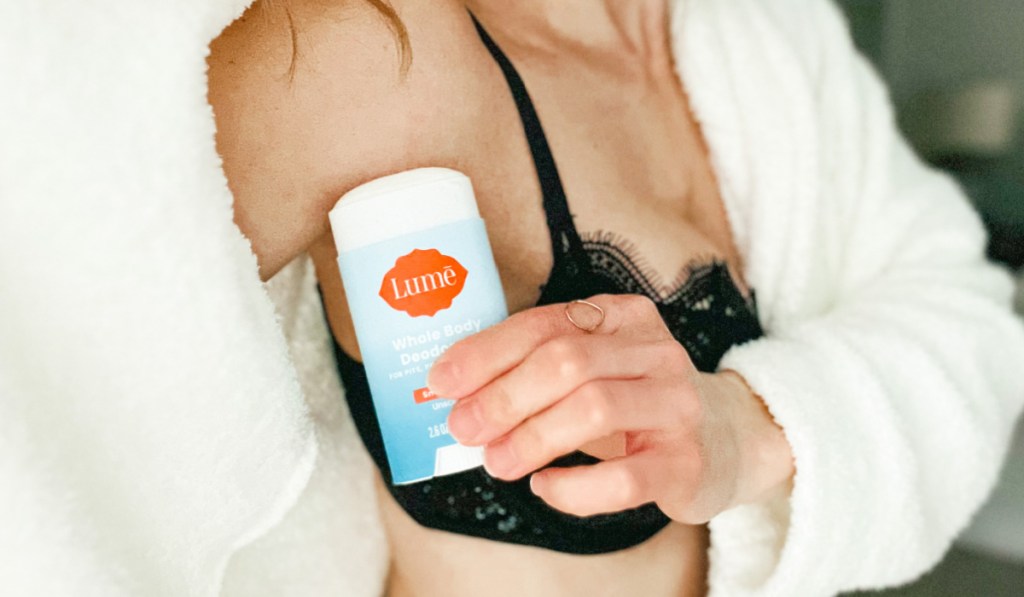woman in bra applying deodorant to underarm