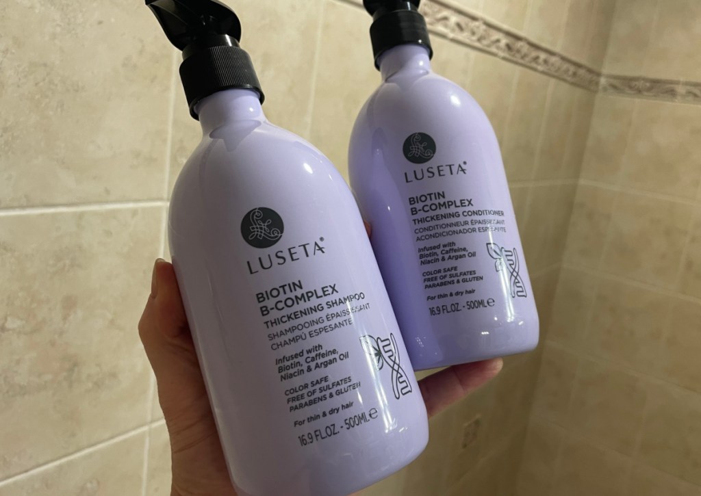 hand holding two purple bottles of shampoo