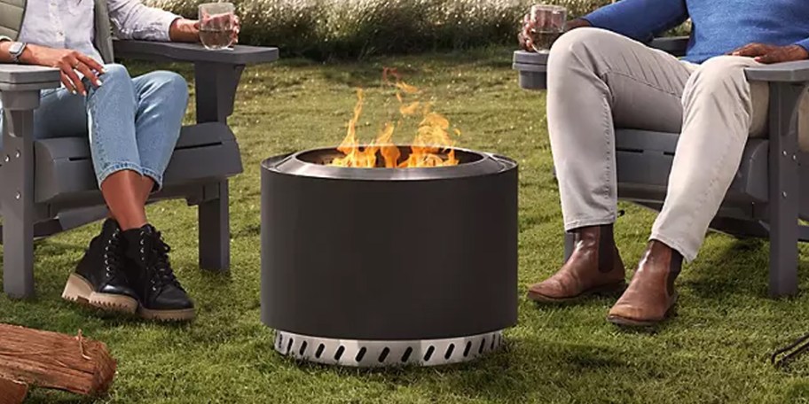 black firepit on grass with people sitting next to it 