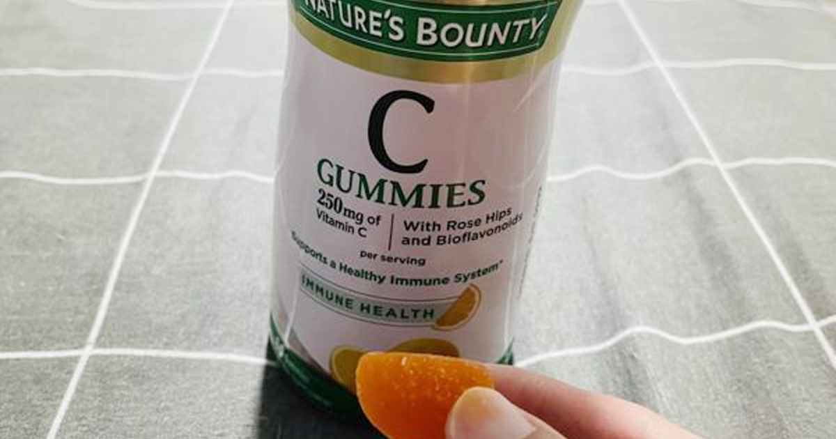 natures bounty gummies bottle with hand holding gummy in front of it