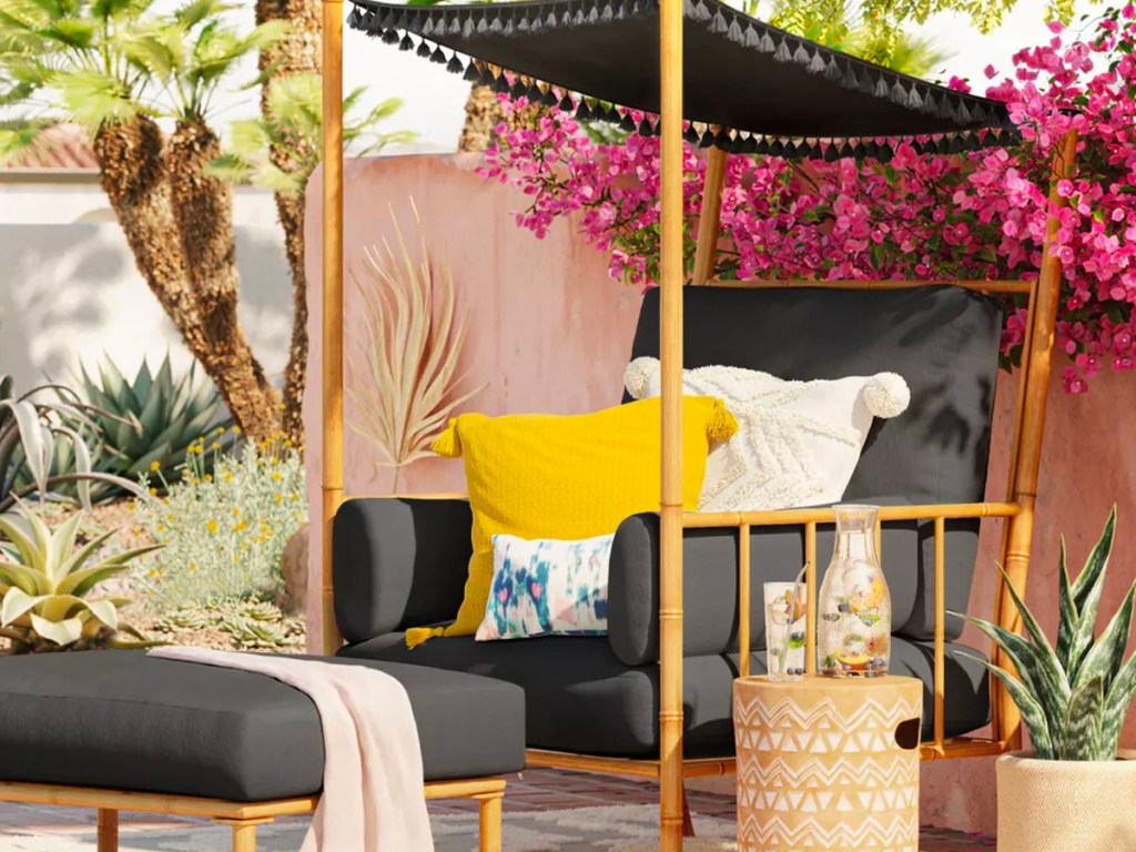 black canopy patio chair with white and yellow pillows on porch