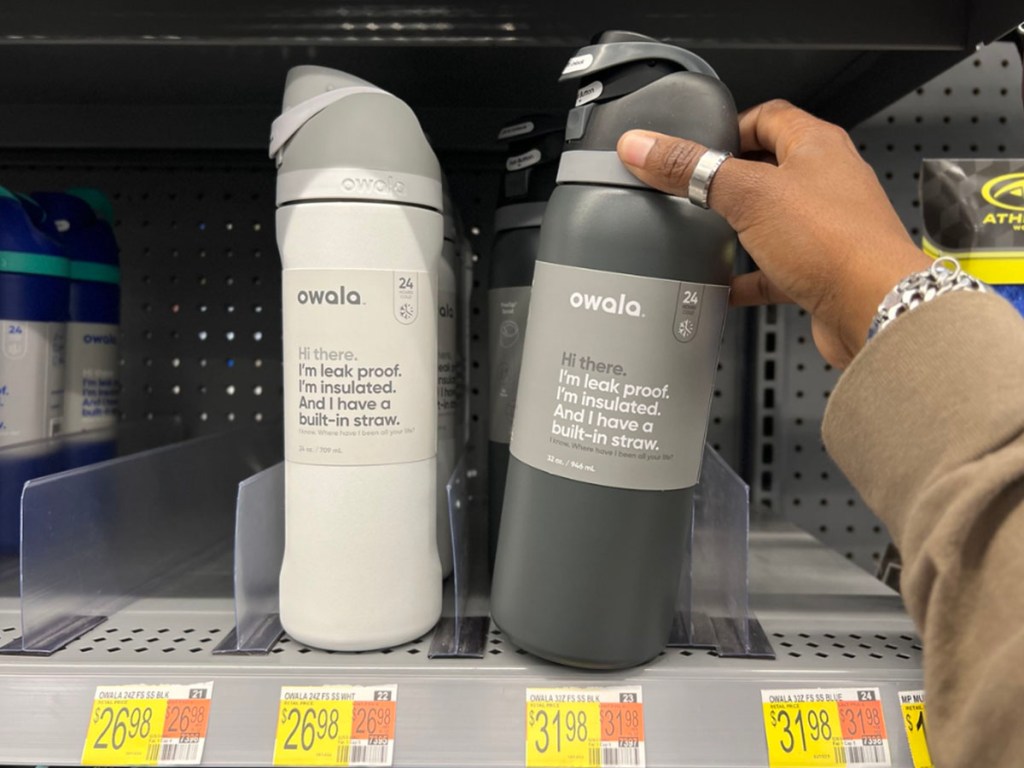 white owala water bottle and womans hand holding gray owala water bottle on shelf
