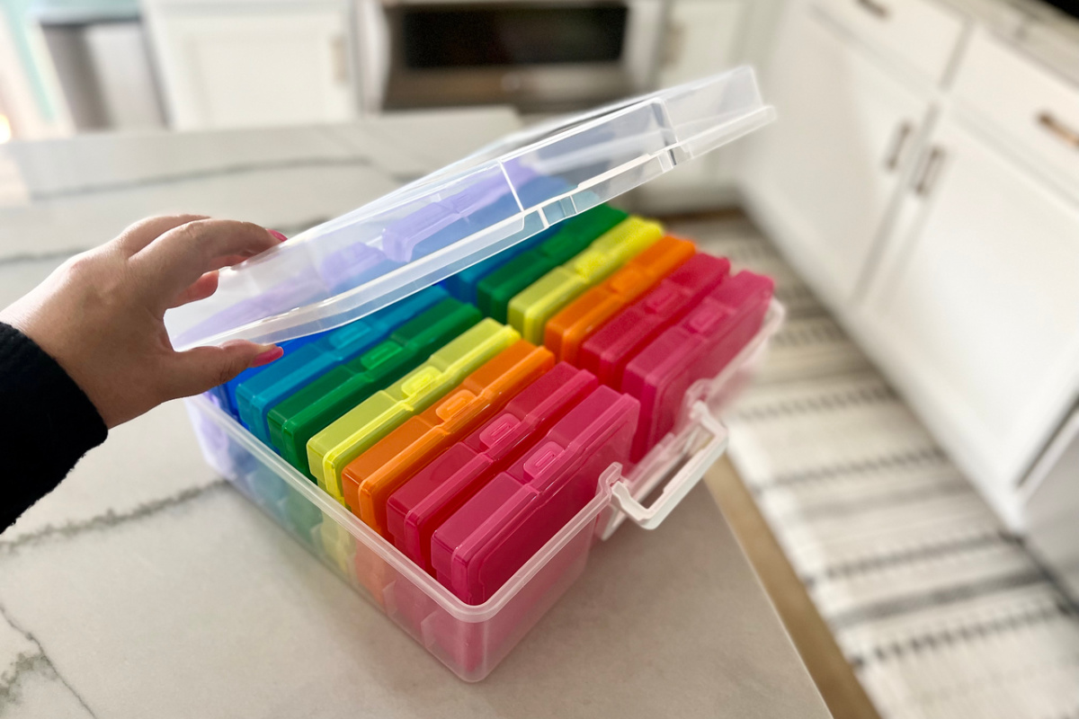 woman opening the lid on an multi-colored photo and craft keeper