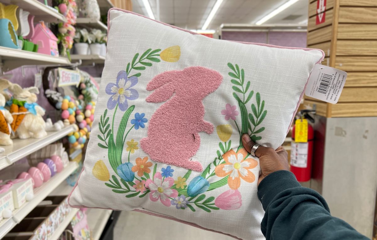 a woman's hand holding up a pink bunny pillow