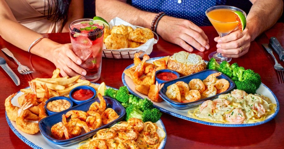 two shrimp entrees and beverages on a red table