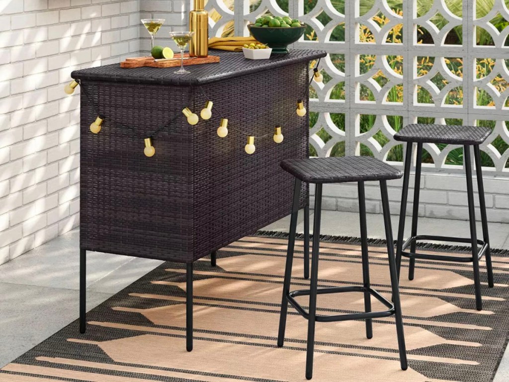 black wicker bar and stool set with lights hanging on it on patio