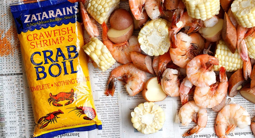seafood boil seasons on newspaper with shrimp, potatoes and corn on it